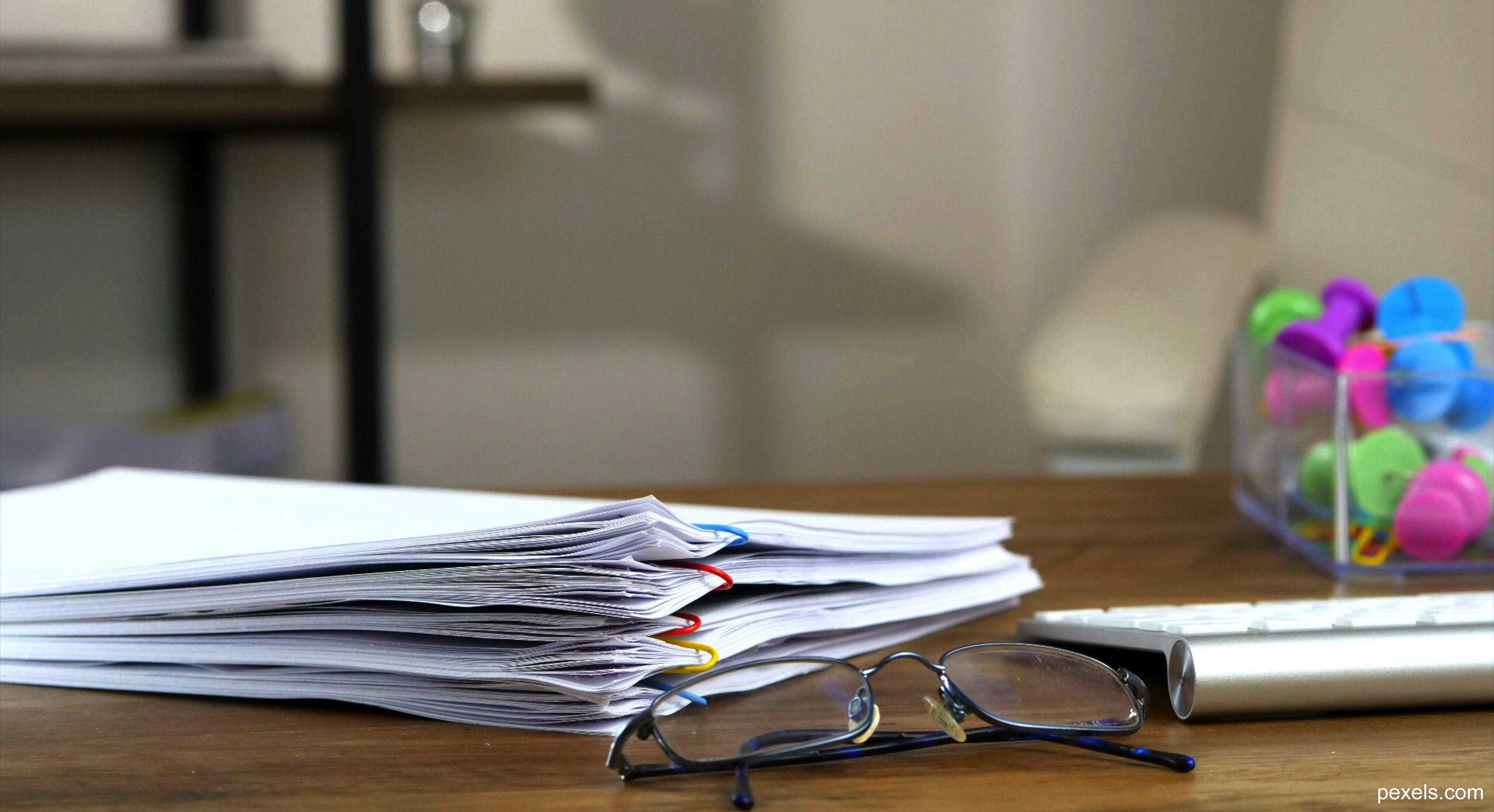 Image depicting several versions of a manuscript and reading glasses, referencing the proof-reading and peer-review the book has gone through.